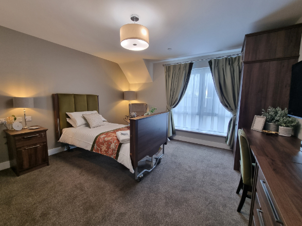 a spacious care home bedroom with single profiling bed
