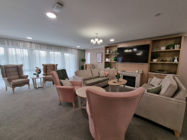 care home lounge with beige and pink sofas and a large television